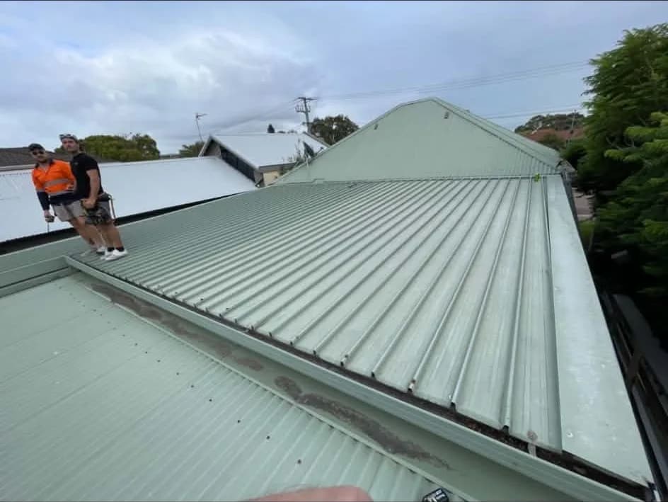 Roofing crew on a pale green Colorbond corrugated roof