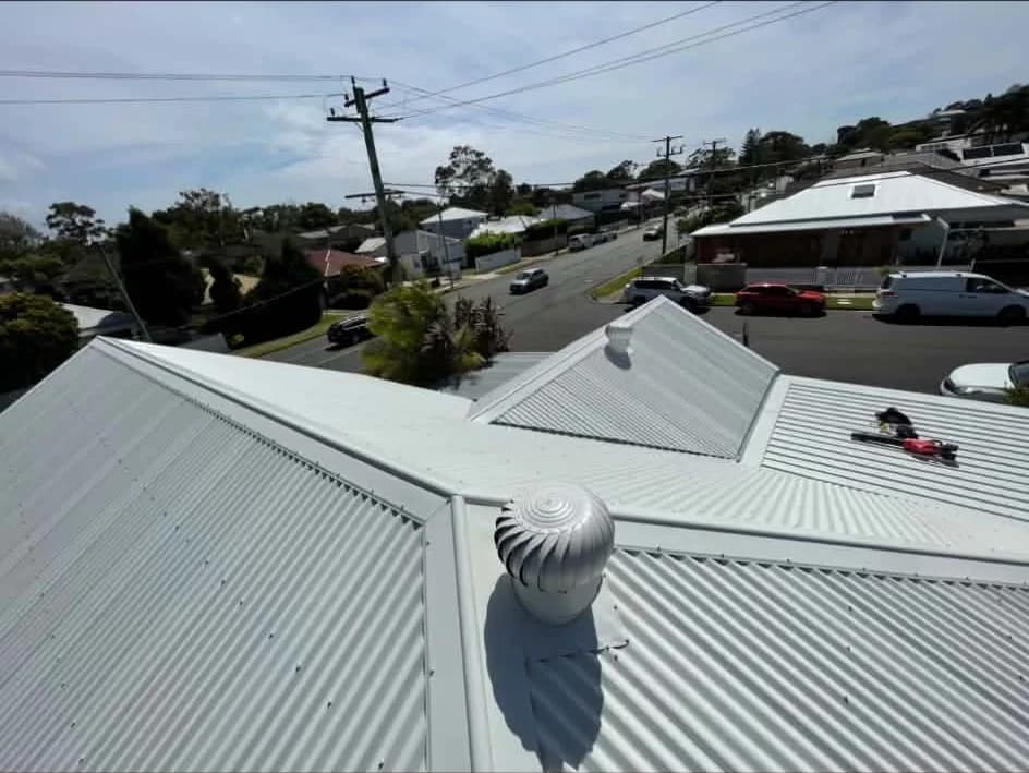 Finished light-coloured Colorbond corrugated roof with whirlybirds and hips